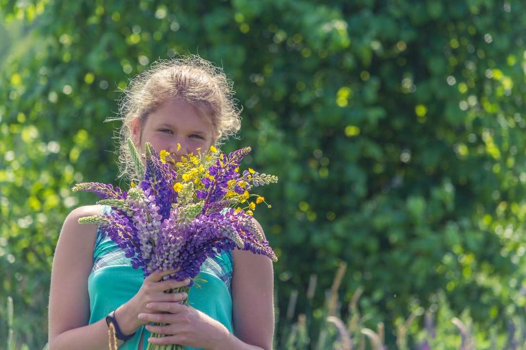 dziewczyna w niebieskiej sukience bez rękawów, trzymając fioletowy kwiat puzzle online