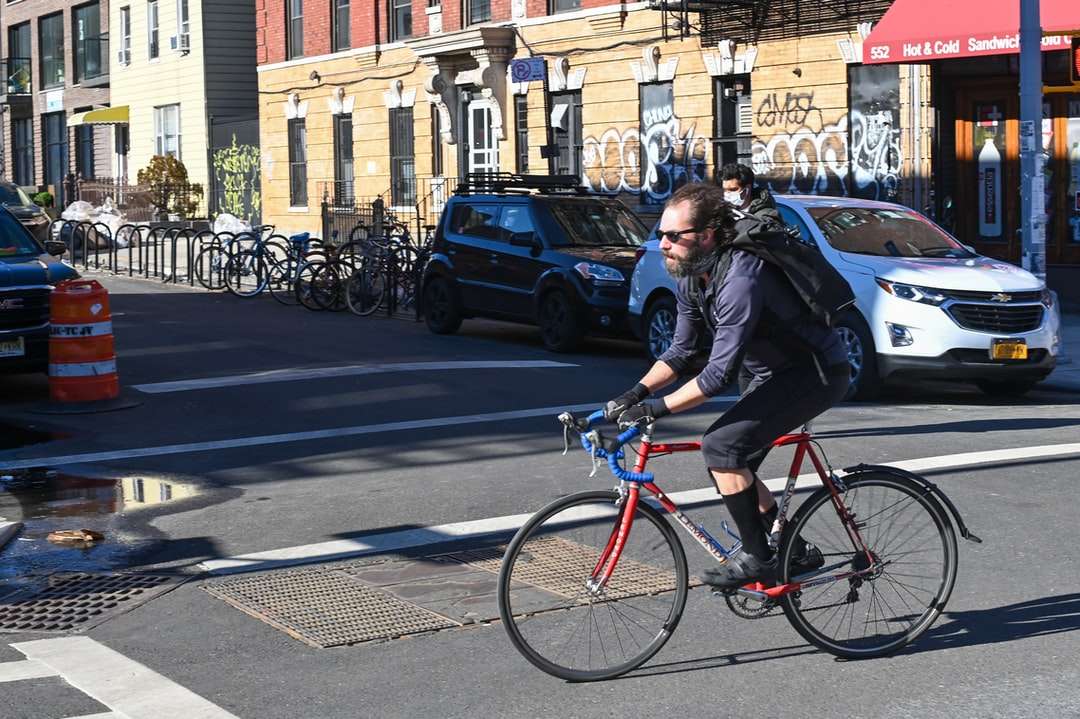 mężczyzna w czarnej kurtce, jazda na czerwonym rowerze na drodze puzzle online