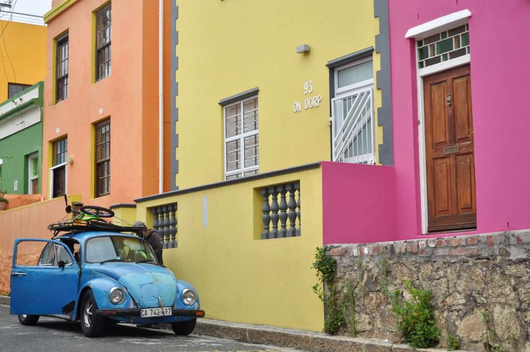 niebieski samochód zaparkowany obok żółtego betonowego budynku puzzle online