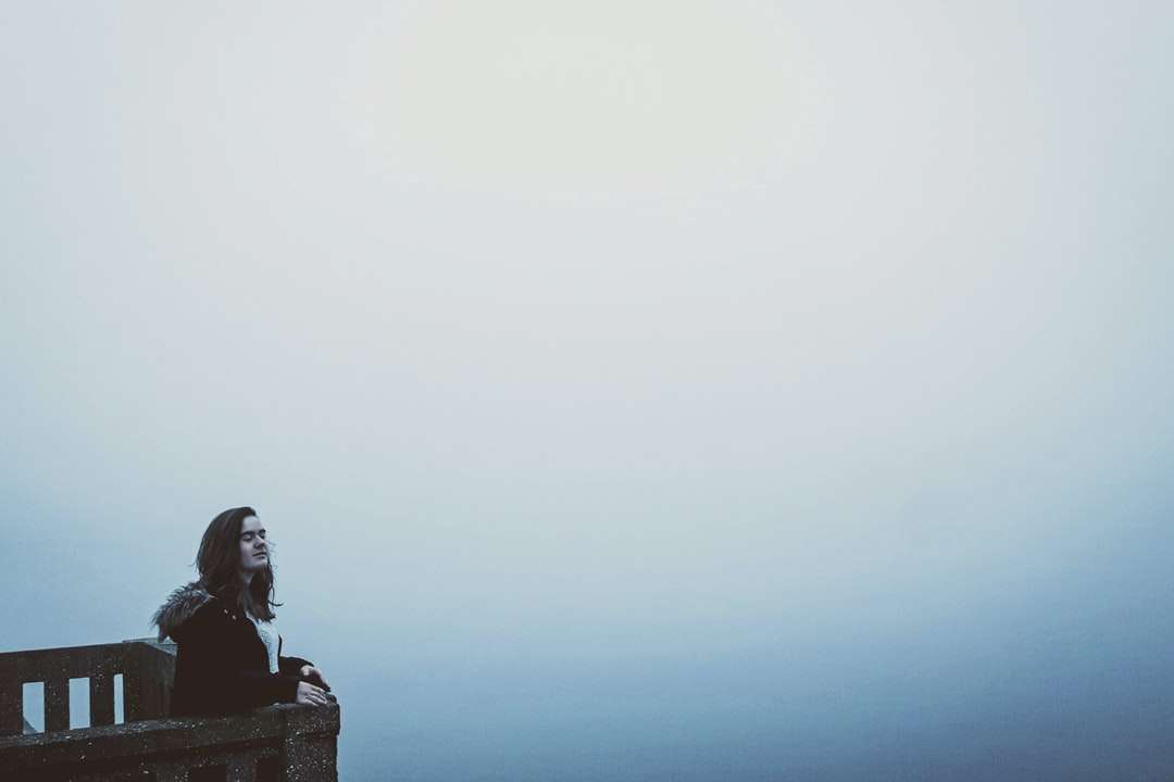 kobieta siedzi na skale pod białym niebem w ciągu dnia puzzle online