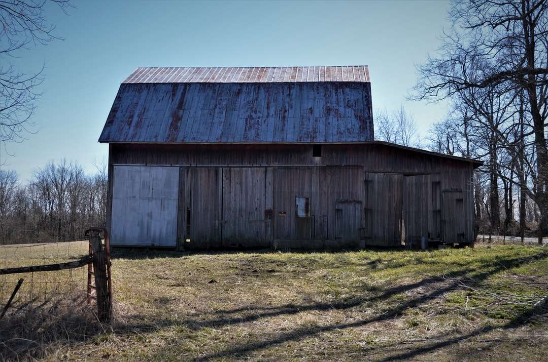 brązowy drewniany dom w stodole w pobliżu nagich drzew w ciągu dnia puzzle online