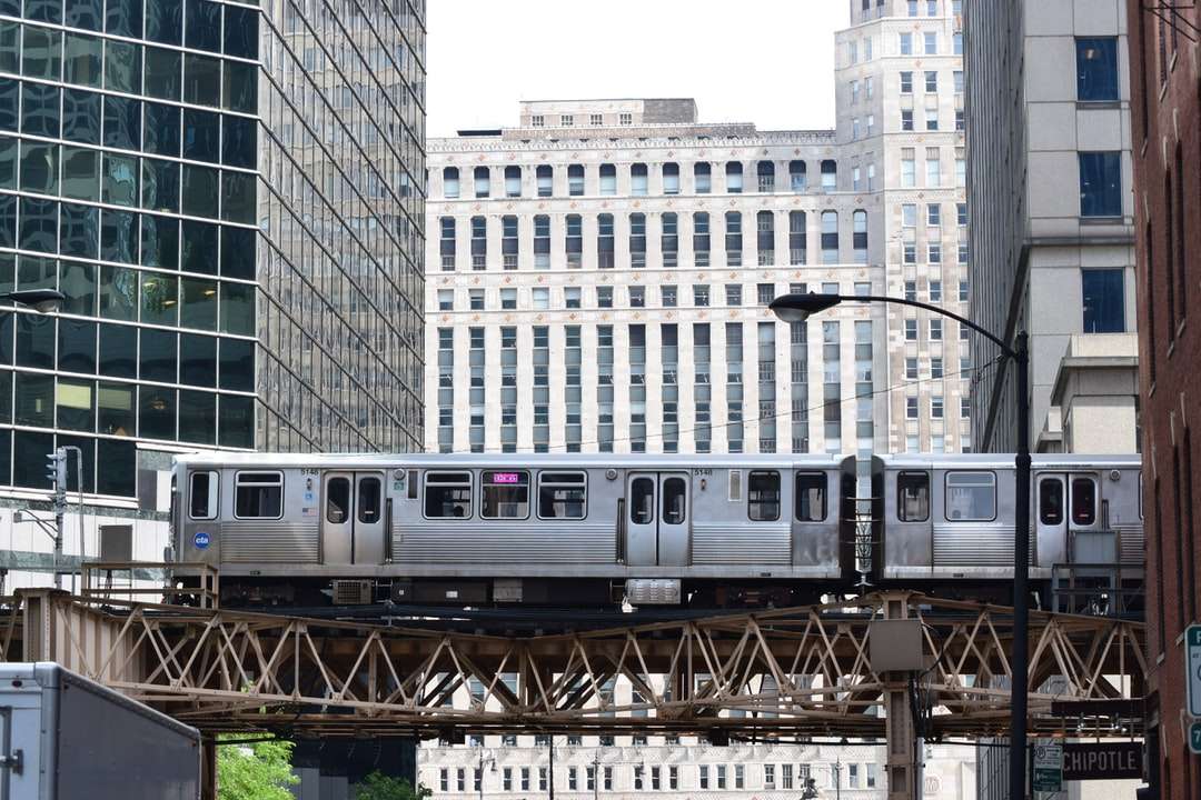 biały pociąg na szynie w pobliżu budynku w ciągu dnia puzzle online