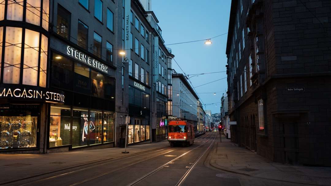 czerwony i biały tramwaj na drodze w pobliżu budynku w ciągu dnia puzzle online