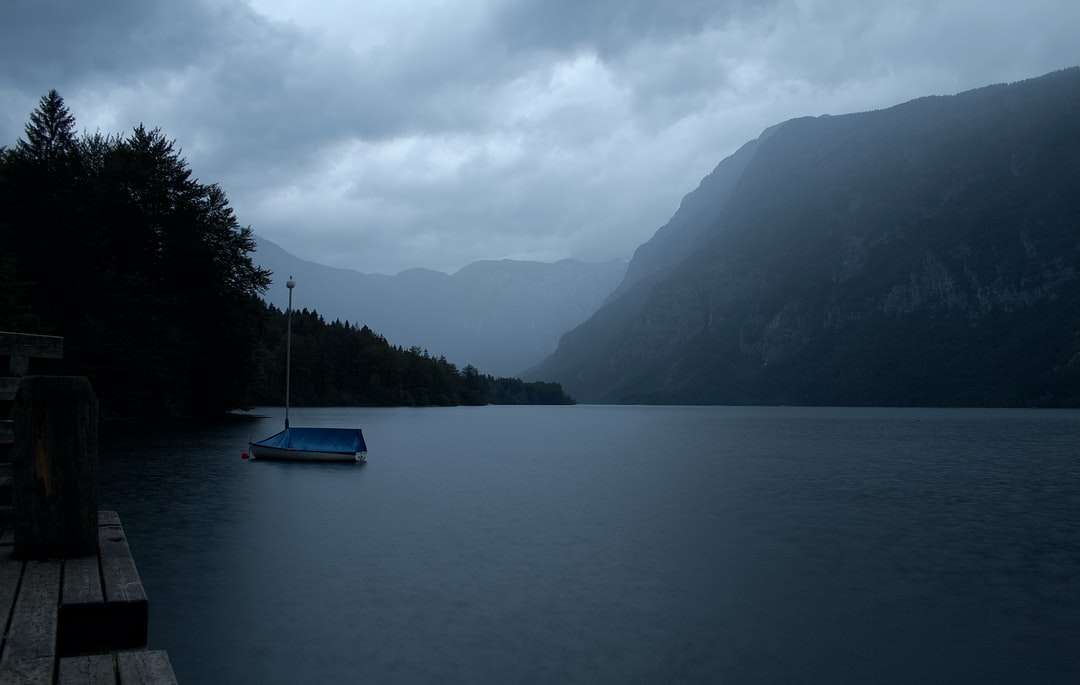 niebieska łódź na zbiorniku wodnym w pobliżu góry w ciągu dnia puzzle online