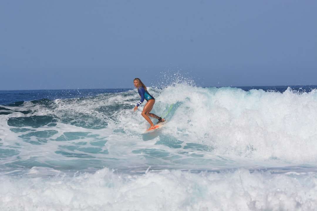 kobieta w niebieskim i białym bikini surfing na falach morza puzzle online
