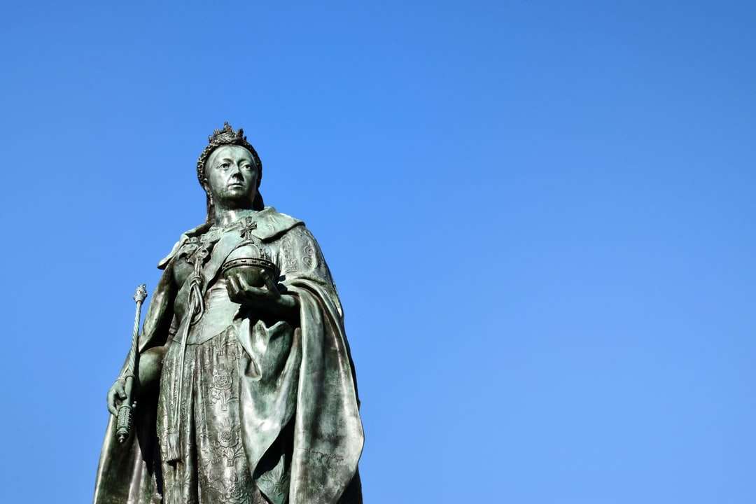 człowiek w płaszczu posąg pod błękitnym niebem w ciągu dnia puzzle online