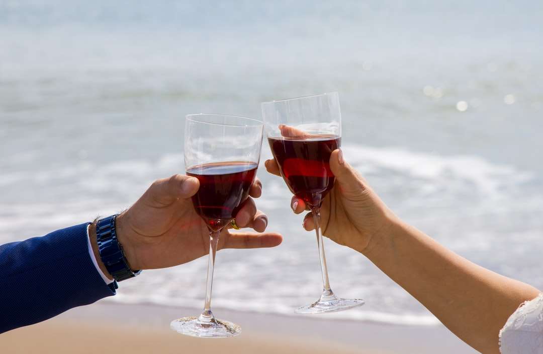2 osoby trzymające bezbarwny kieliszek do wina czerwonego puzzle online