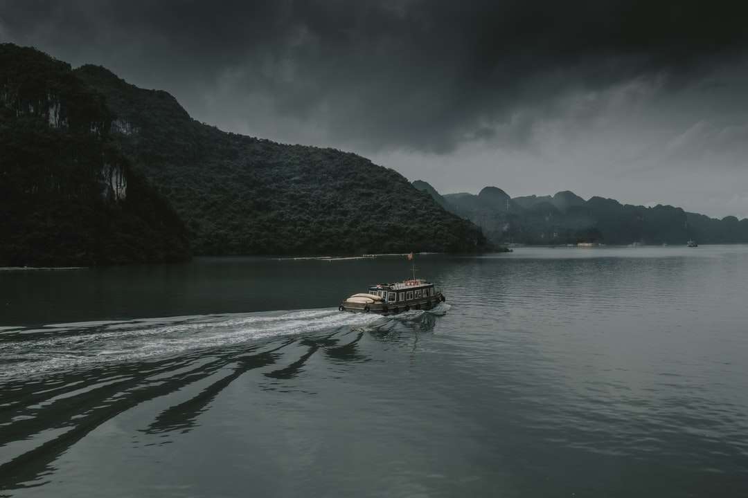 brązowa łódź na zbiorniku wodnym w pobliżu góry w ciągu dnia puzzle online