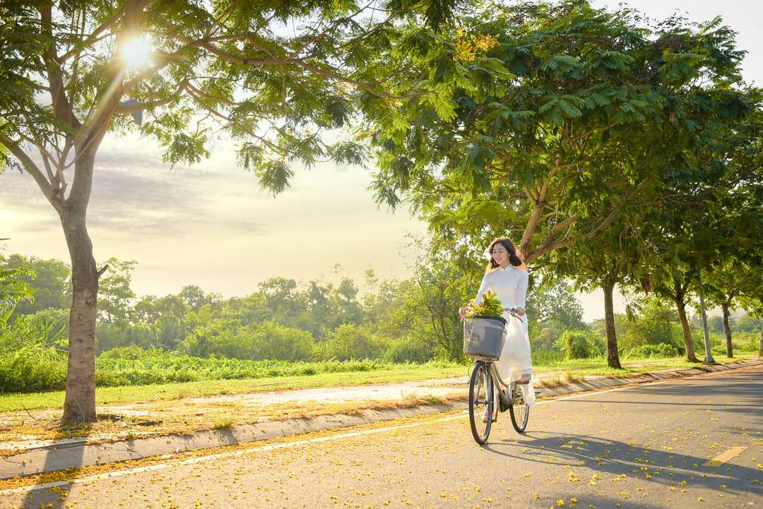 kobieta w białej koszuli, jazda na rowerze na brązowej polnej drodze puzzle online