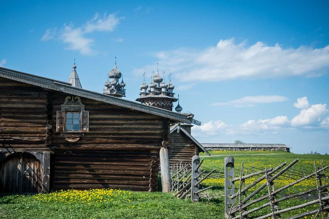 brązowy drewniany dom na zielonym polu trawy pod błękitnym niebem puzzle online