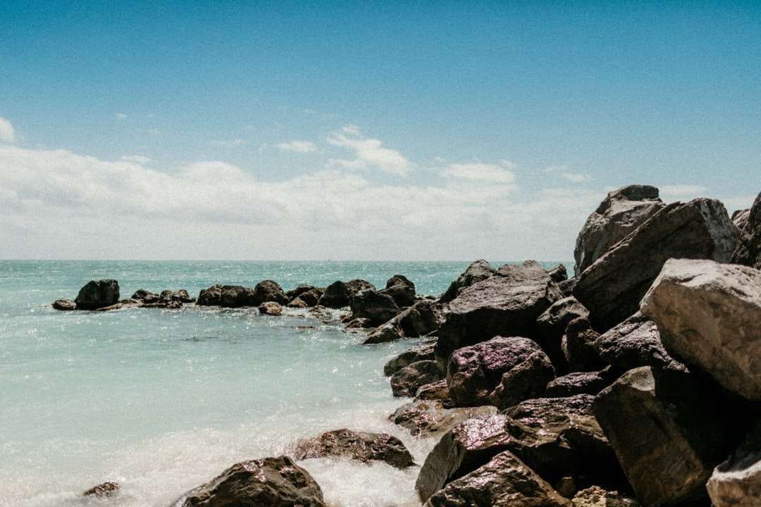 skalisty brzeg ze skałami i wodą oceanu pod błękitnym niebem puzzle online