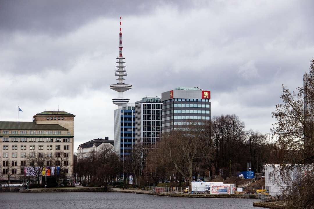 biało-czerwona wieża w pobliżu budynków miejskich pod białymi chmurami puzzle online