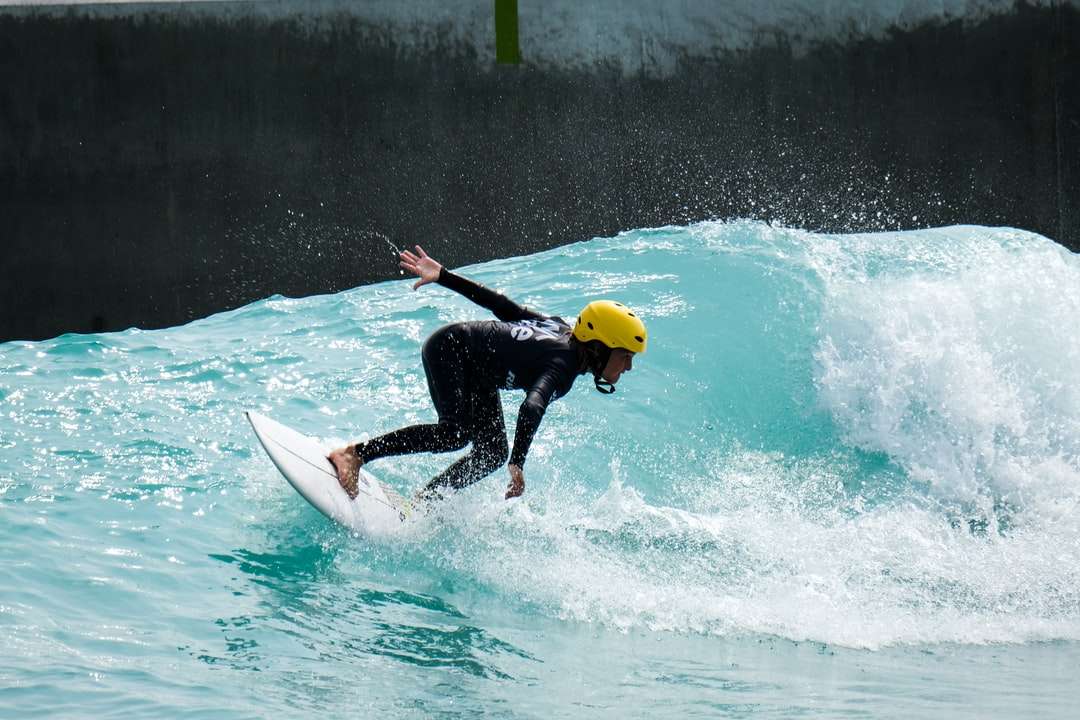 Mężczyzna w czarnym mokrym kostiumu jedzie na białej surfboard podczas dnia puzzle online
