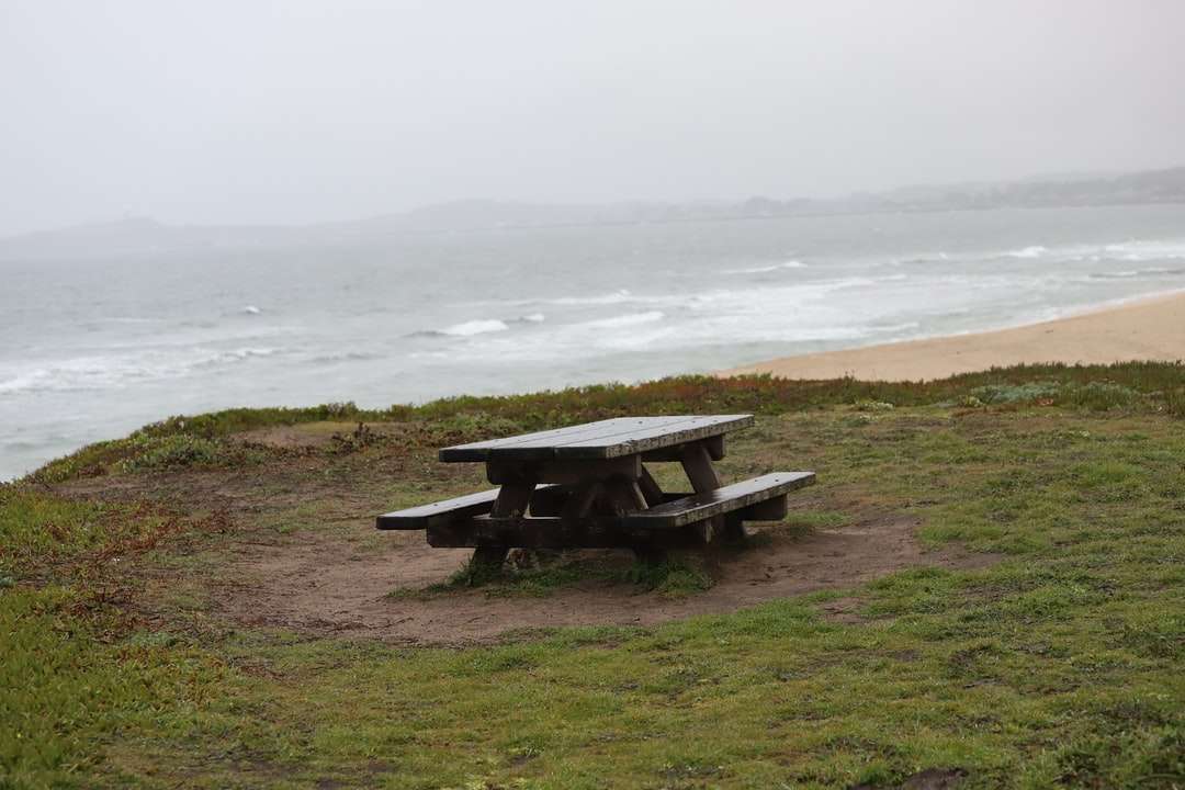 Brązowy drewniany stół piknikowy na zielonej trawie polu blisko ciała puzzle online