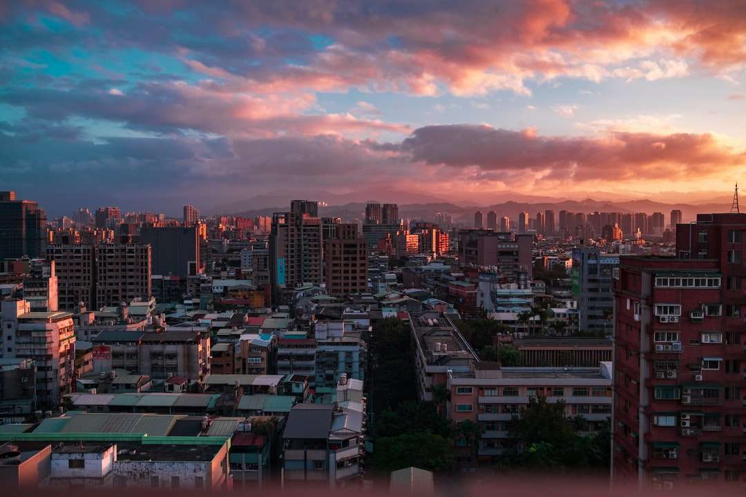 Skyline miasta pod pomarańczowym i szarej chmurne niebo podczas zachodu słońca puzzle online