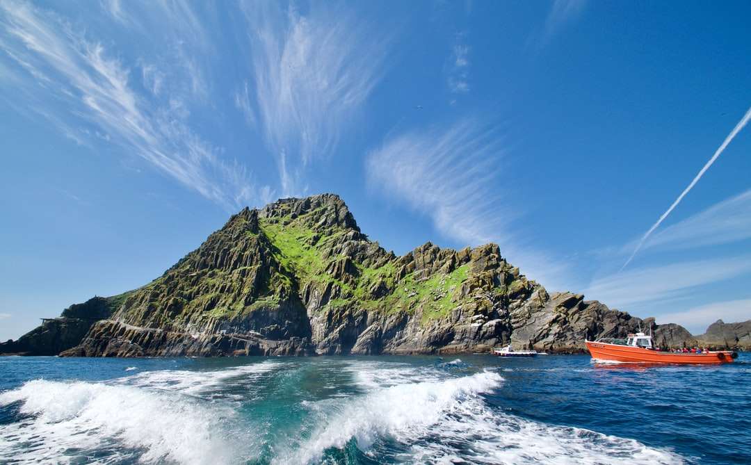 Zielona i brązowa formacja skalna na morzu pod błękitnym niebem puzzle online