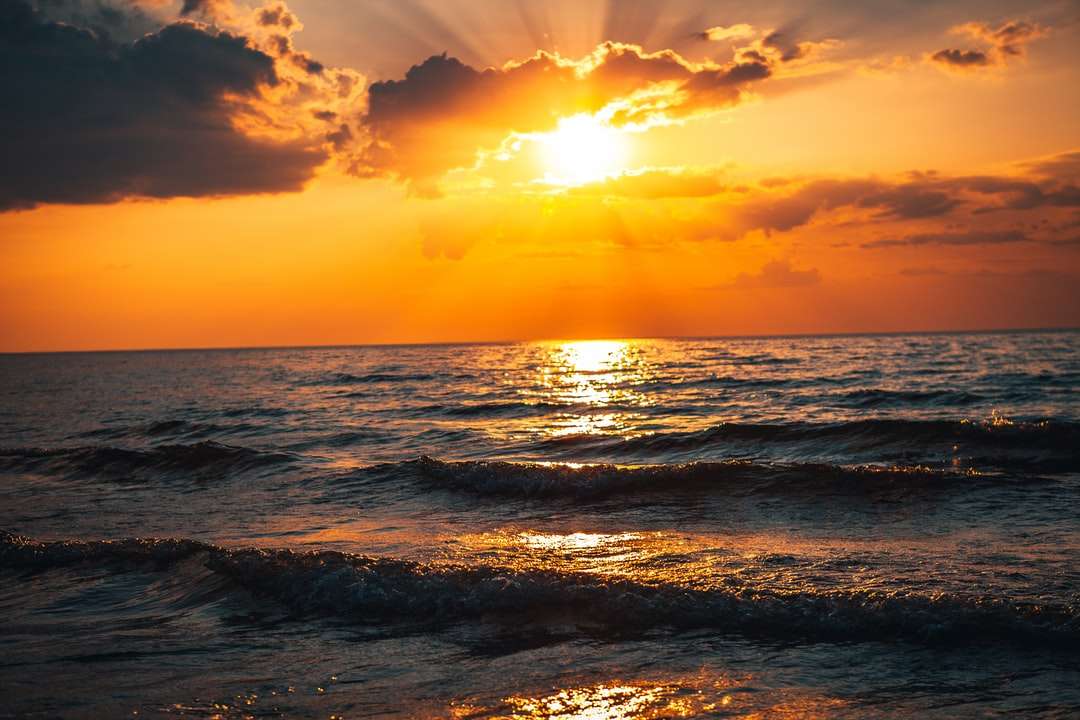 Fale morskie rozbijające się na brzegu podczas zachodu słońca puzzle online