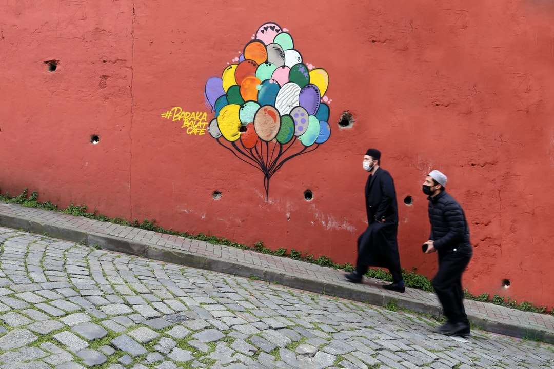 Ludzie chodzą na chodniku w pobliżu czerwonej ściany puzzle online