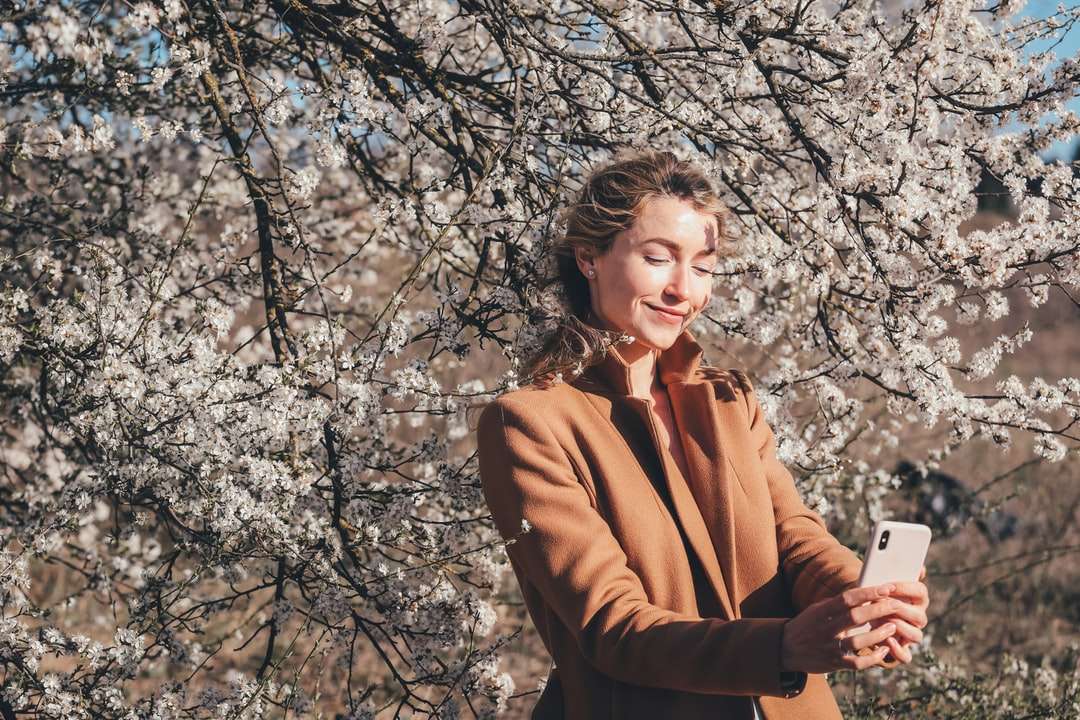 Kobieta w brown płaszcz stoi blisko brązowego drzewa podczas dnia puzzle online
