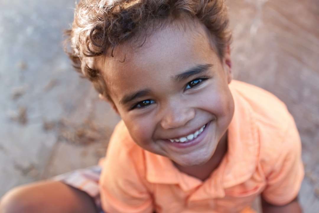Chłopiec w pomarańczowej koszulce polo uśmiecha się puzzle online