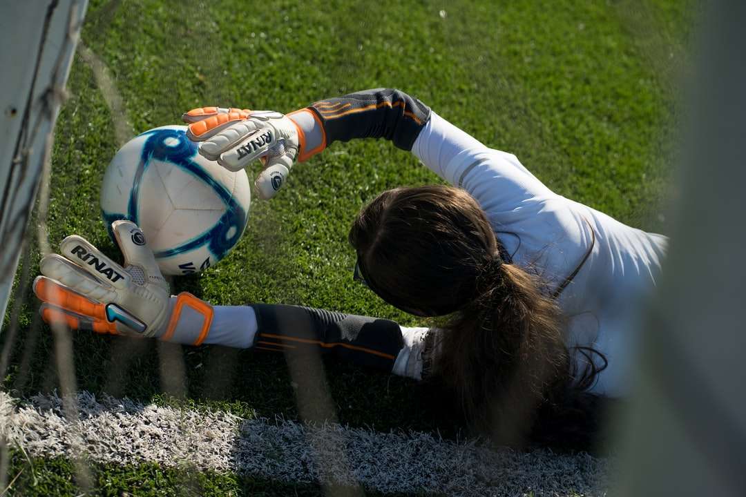 Dziewczyna w białej długiej rękaw koszula bawić się piłkę nożną na polu puzzle online