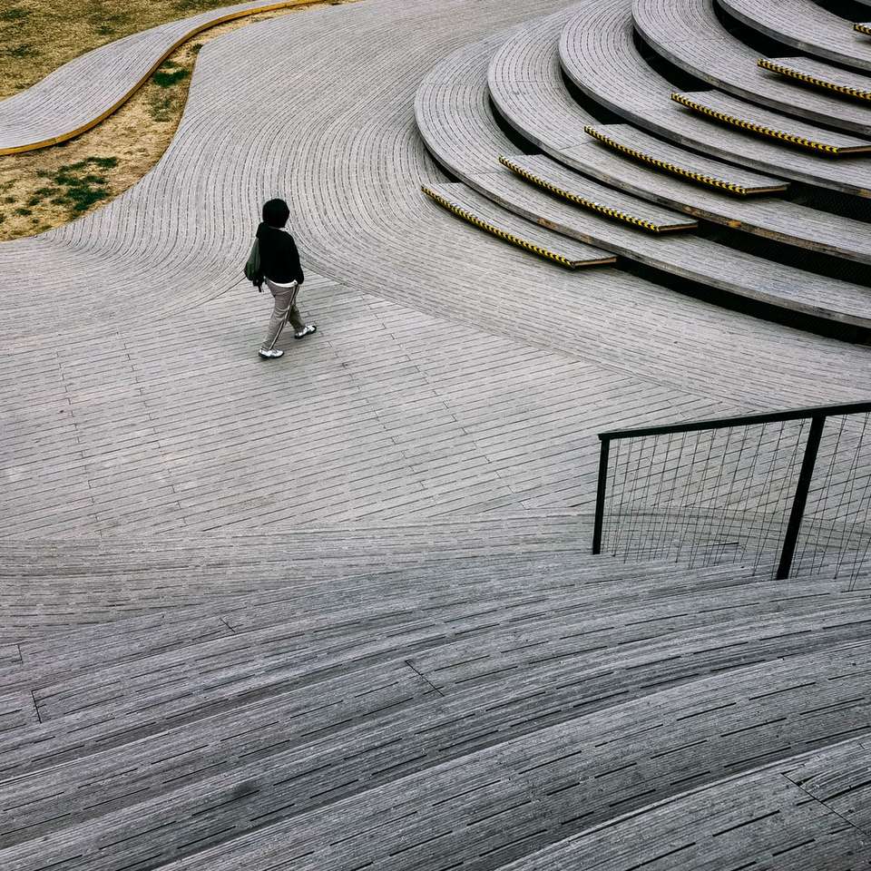 Mężczyzna w czarnej kurtce spaceru na szarym betonowym ścieżce puzzle online