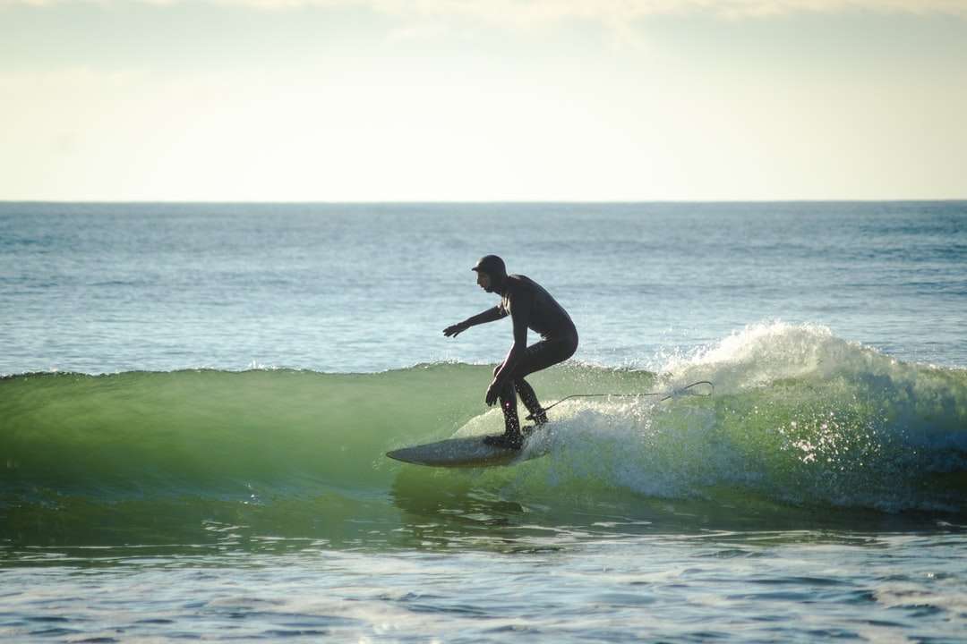 Mężczyzna surfuje na falach morskich w ciągu dnia puzzle online