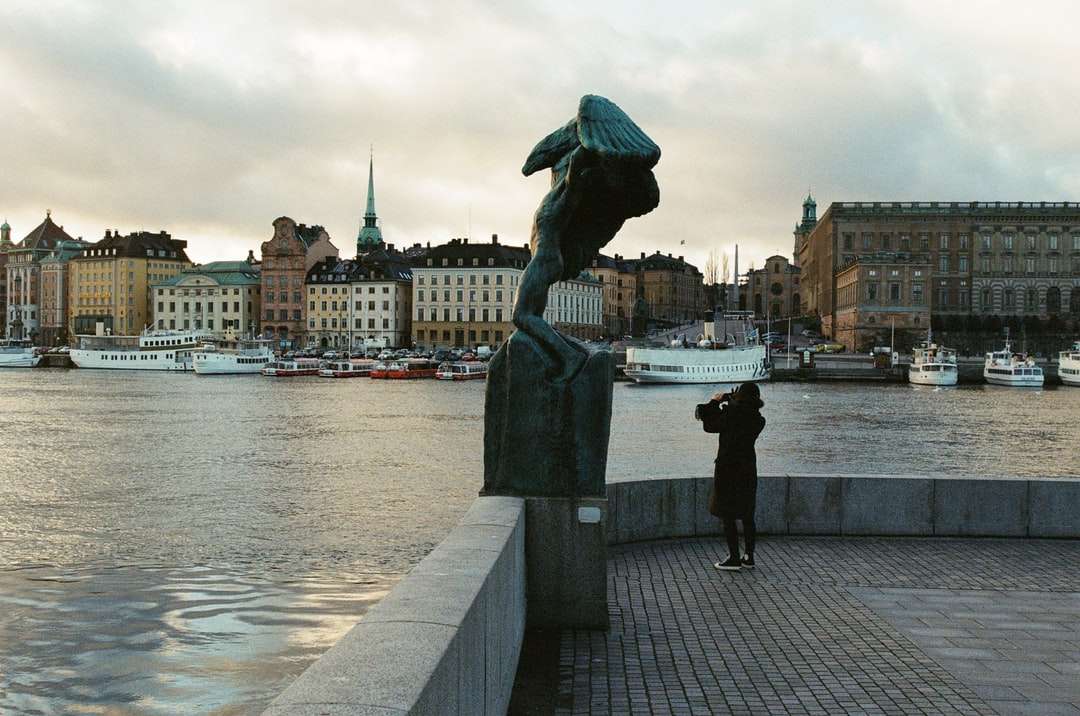Statua mężczyzna trzyma parasol blisko ciała wody puzzle online