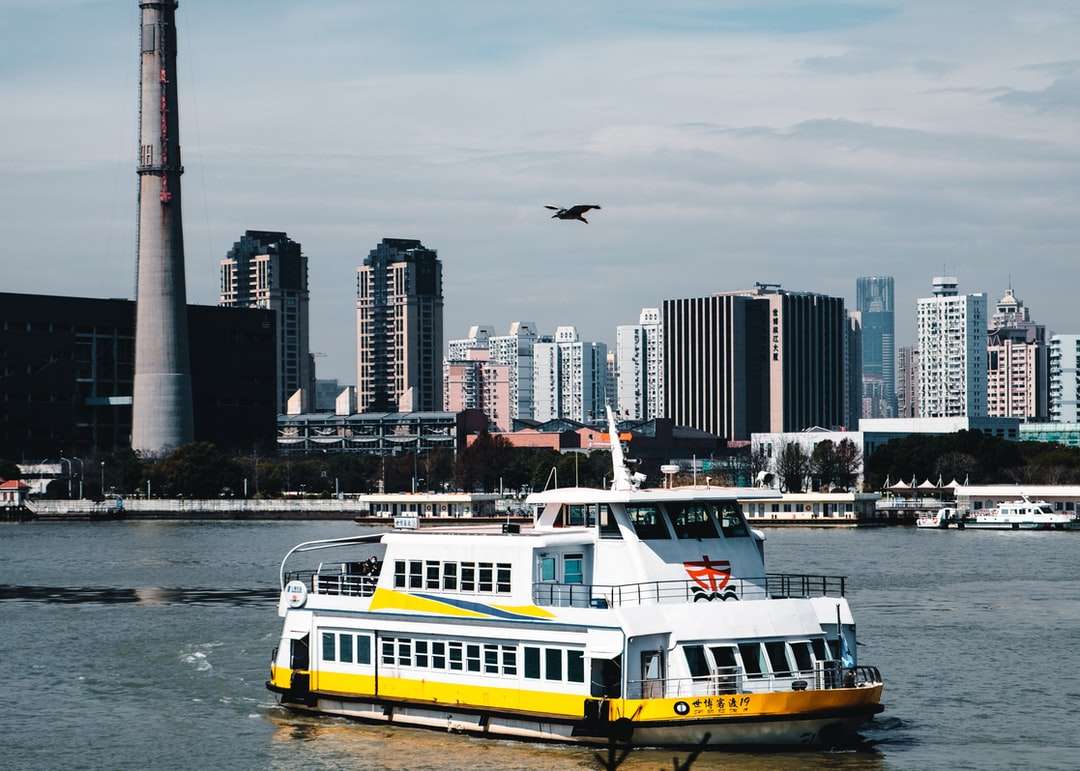 Biała i żółta łódź na wodzie w pobliżu budynków miasta puzzle online
