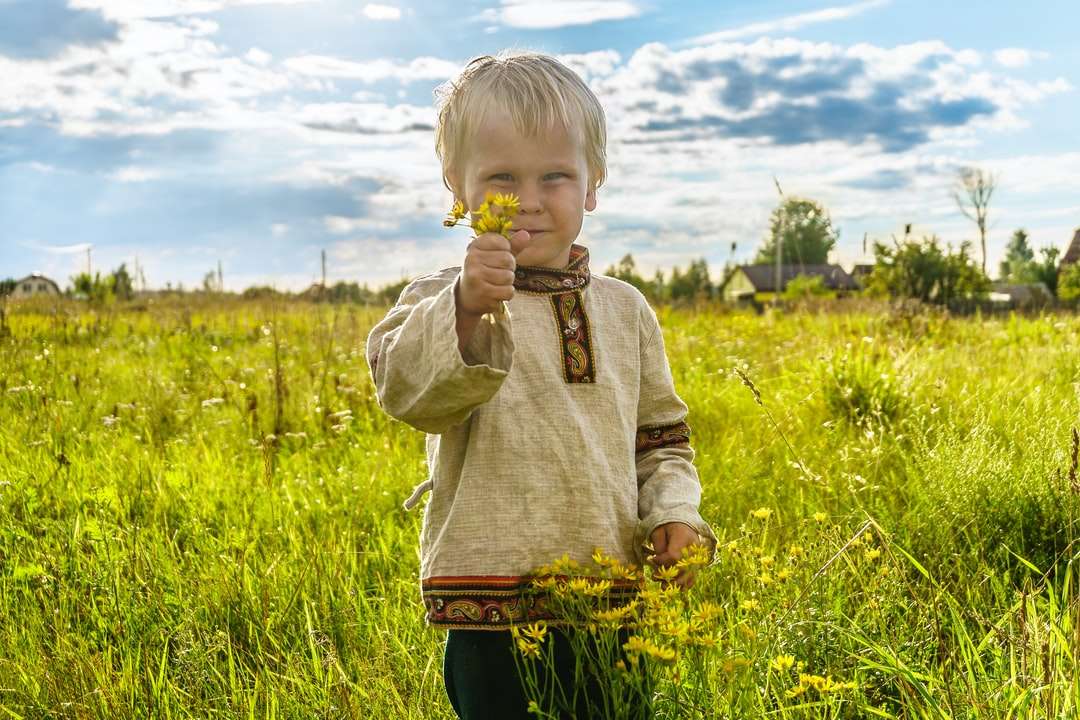 Chłopiec w szarym sweter pozyci na zielonej trawy polu puzzle online