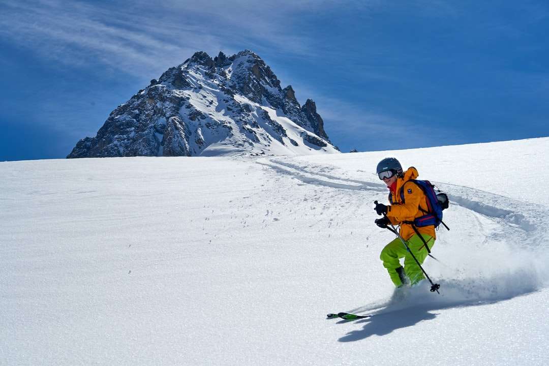 Człowiek w pomarańczowej kurtce i czarne spodnie jeździć na nartach puzzle online