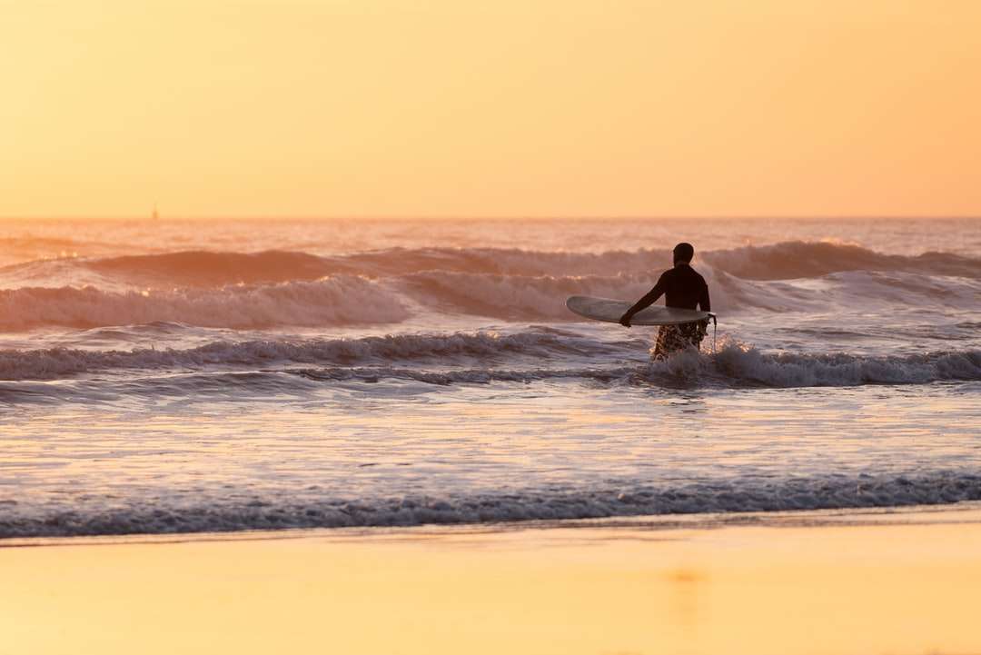 Mężczyzna surfuje na falach morskich podczas zachodu słońca puzzle online
