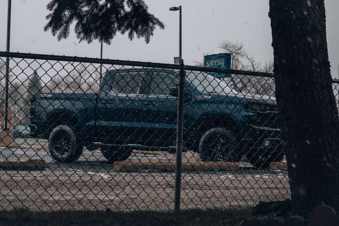 Czarny SUV zaparkowany obok szarego metalowego ogrodzenia w ciągu dnia puzzle online