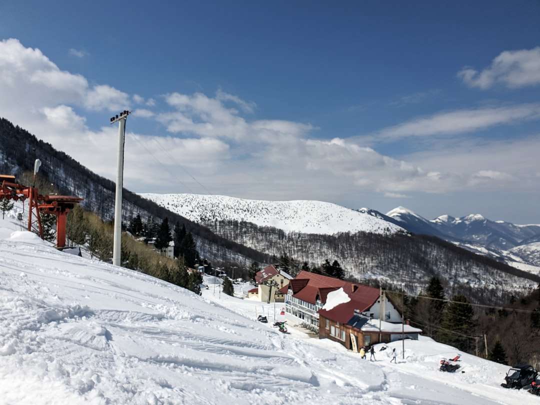 Casas de madeira marrons na terra coberta de neve sob o céu azul quebra-cabeça
