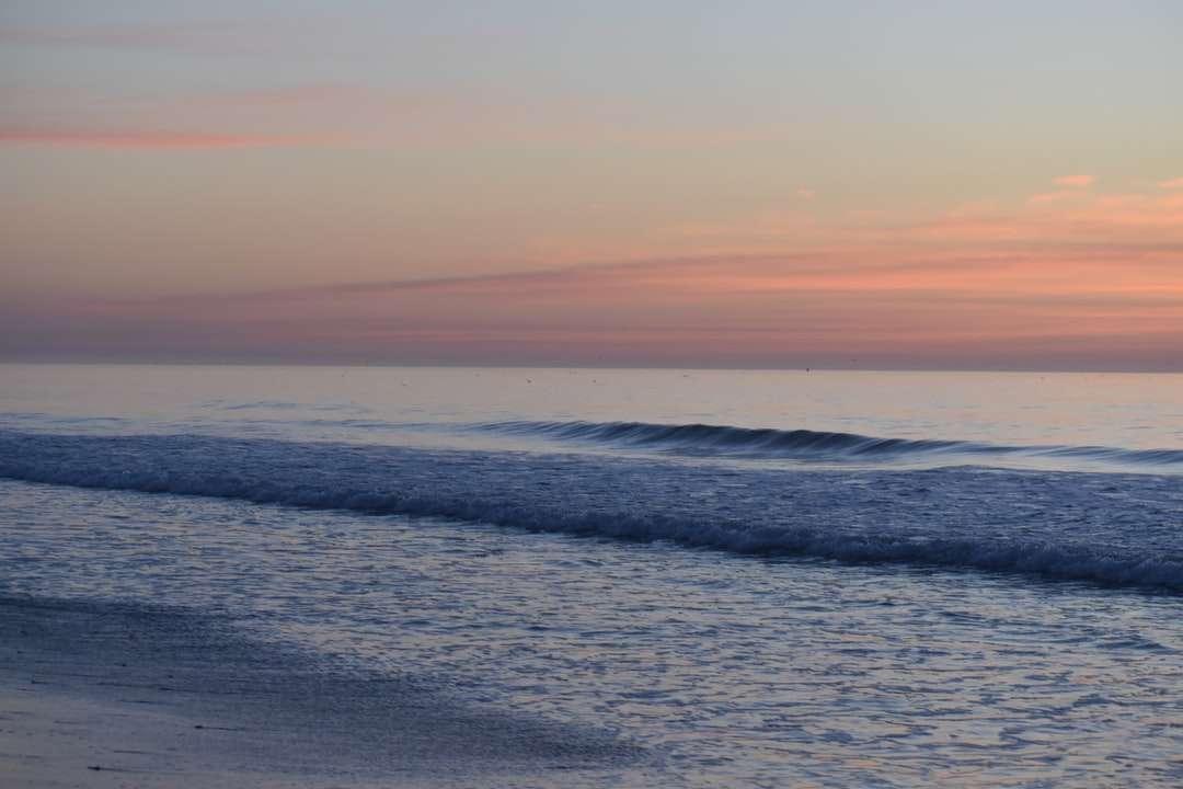 Fale oceanu rozbijające się na brzegu podczas zachodu słońca puzzle online