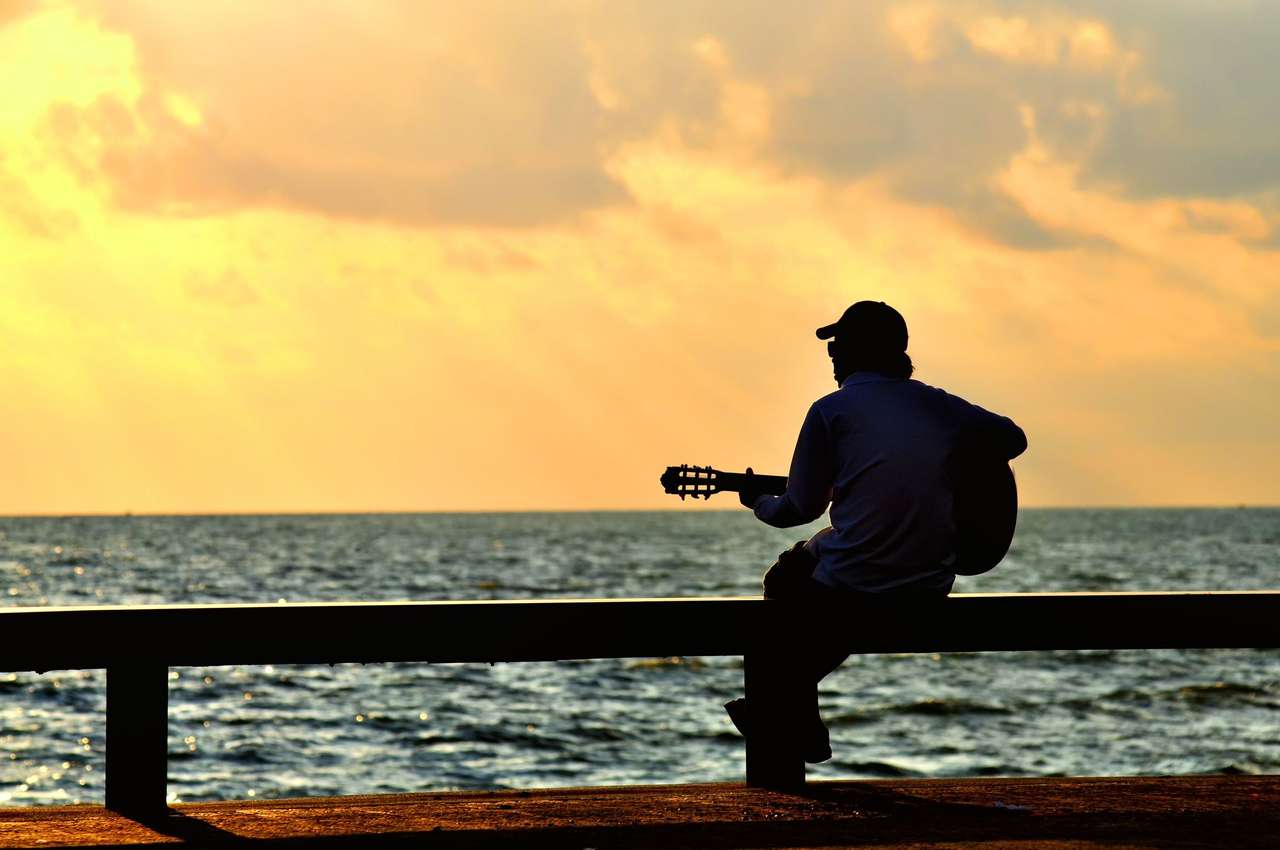 Mężczyzna z gitarą przy zachodzie słońca puzzle