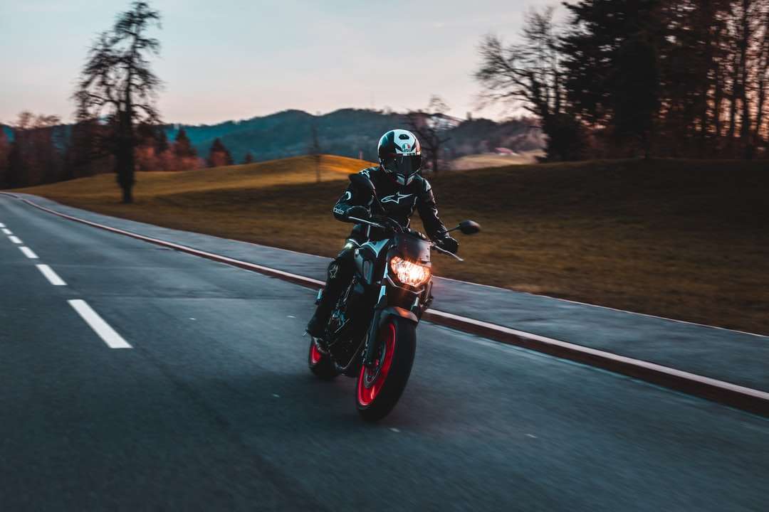 Mężczyzna w czarnym kasku jedzie motocyklu na drodze w ciągu dnia puzzle online