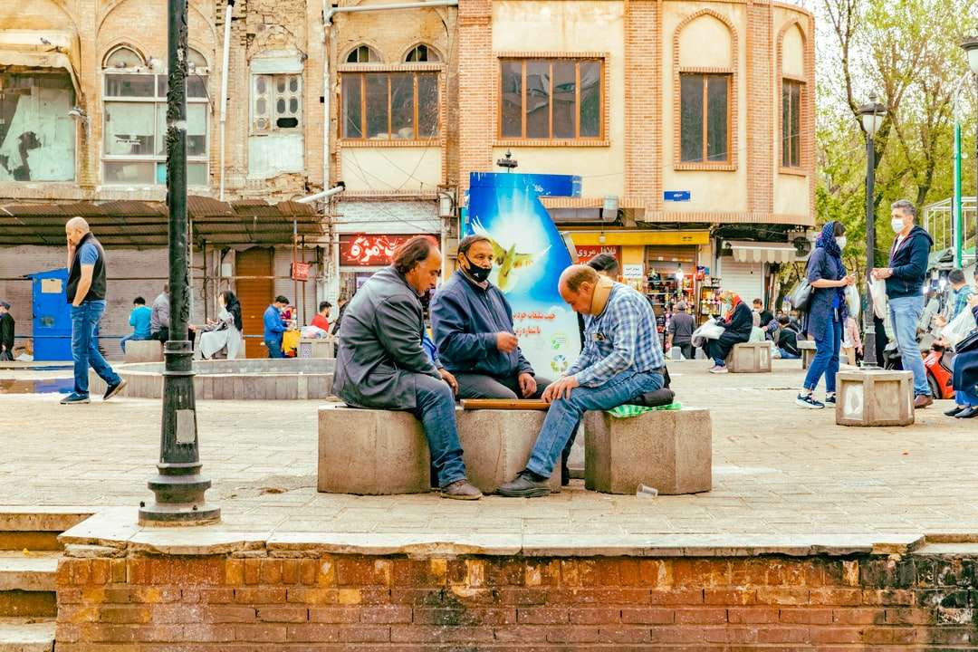 Mężczyzna w niebieskich dżinsach obsiadanie na szare betonowej ławce puzzle online