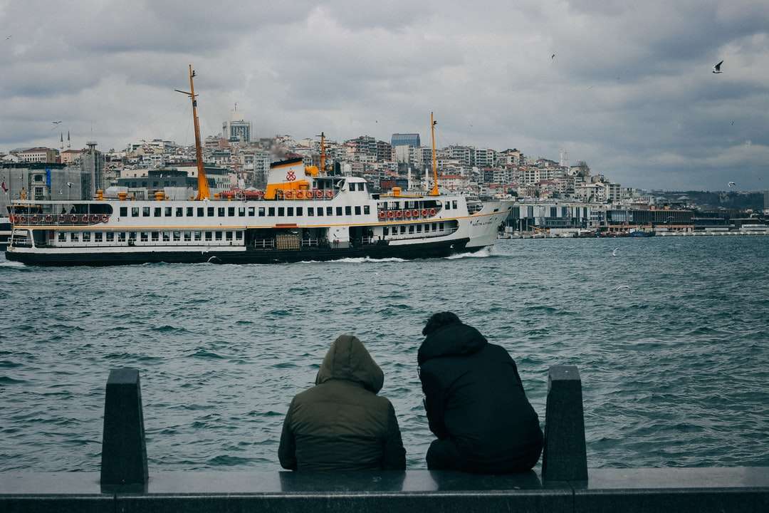 Mężczyzna w czarnym bluzie siedzi na krawędzi łodzi patrząc puzzle online