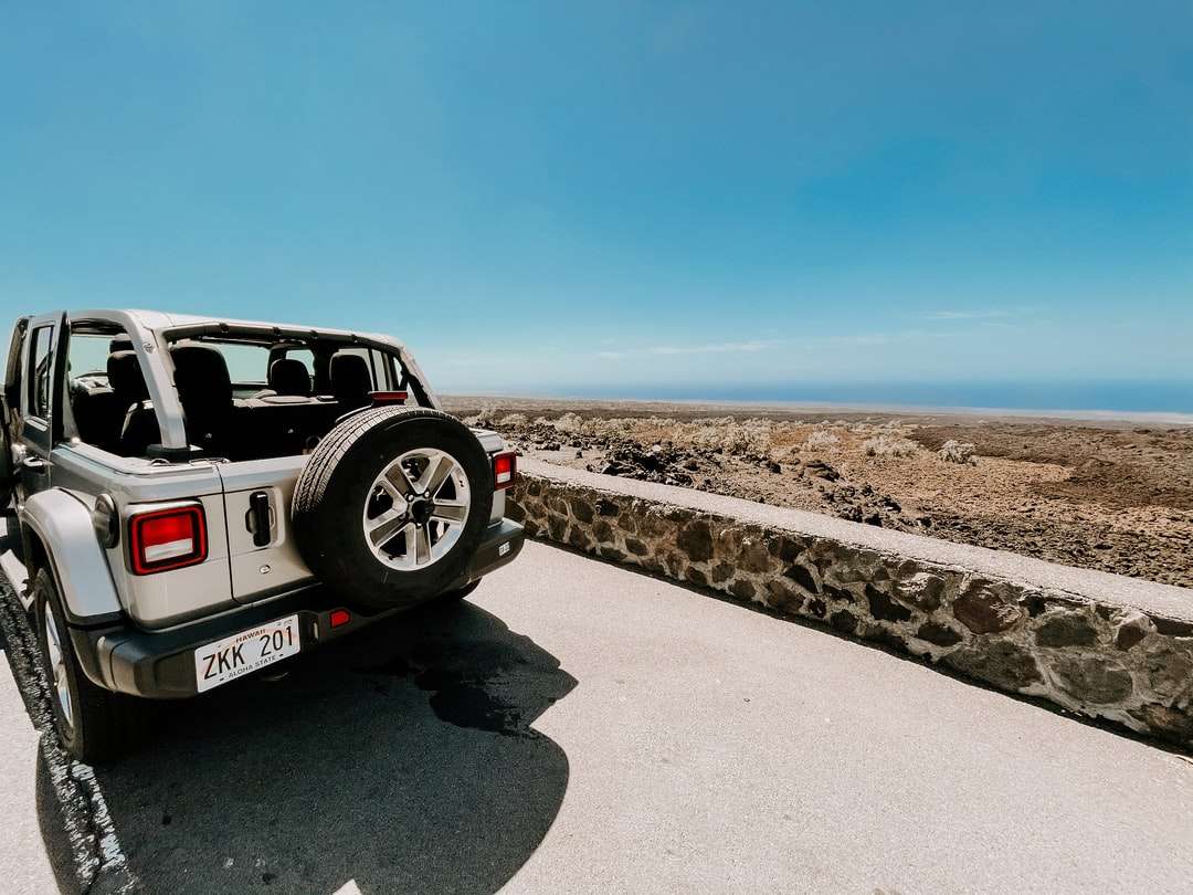 Biały i czarny SUV na szarym piasku pod błękitnym niebem puzzle online