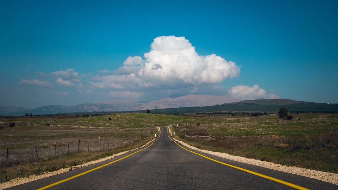 Szara betonowa droga pod błękitnym niebem i białymi chmurami puzzle online