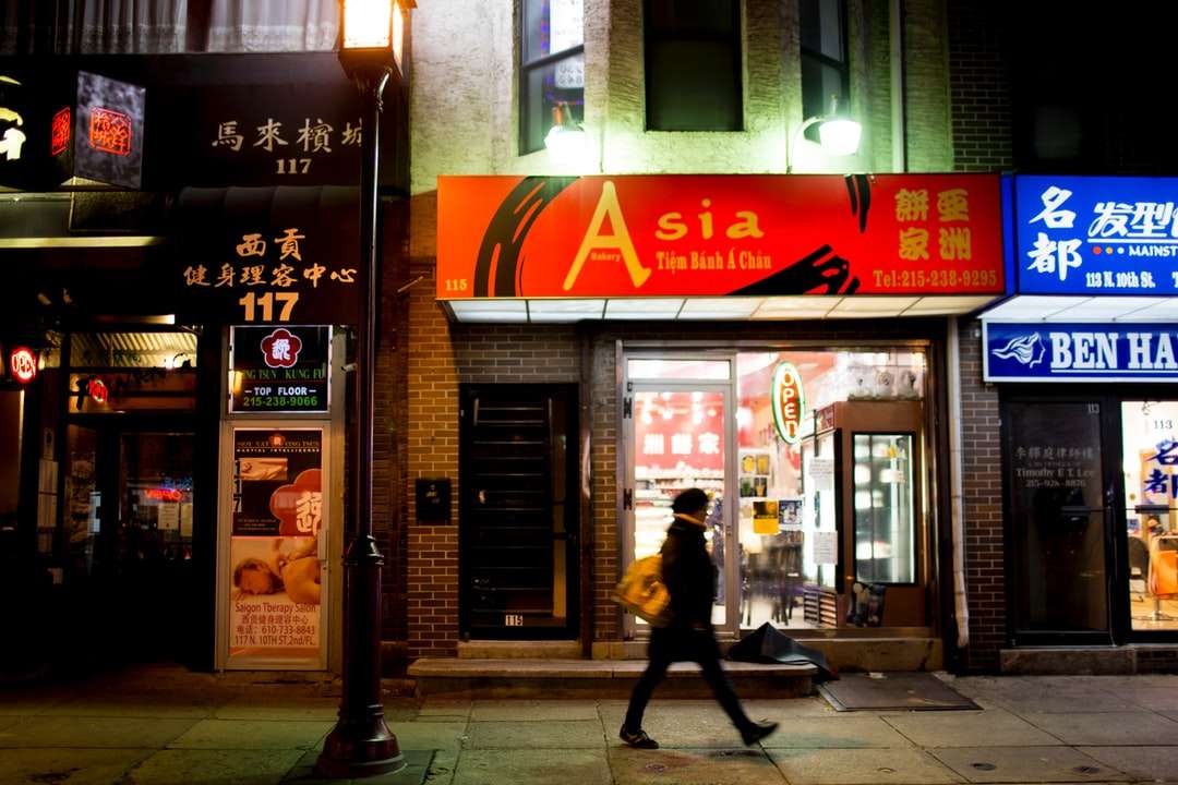 Mężczyzna w czarnej kurtce spaceru na chodniku w pobliżu sklepu puzzle online