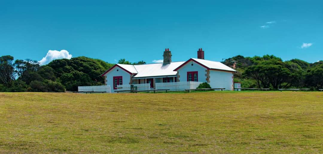Biały i czerwony dom na zielonej trawie polu pod błękitnym niebem puzzle online
