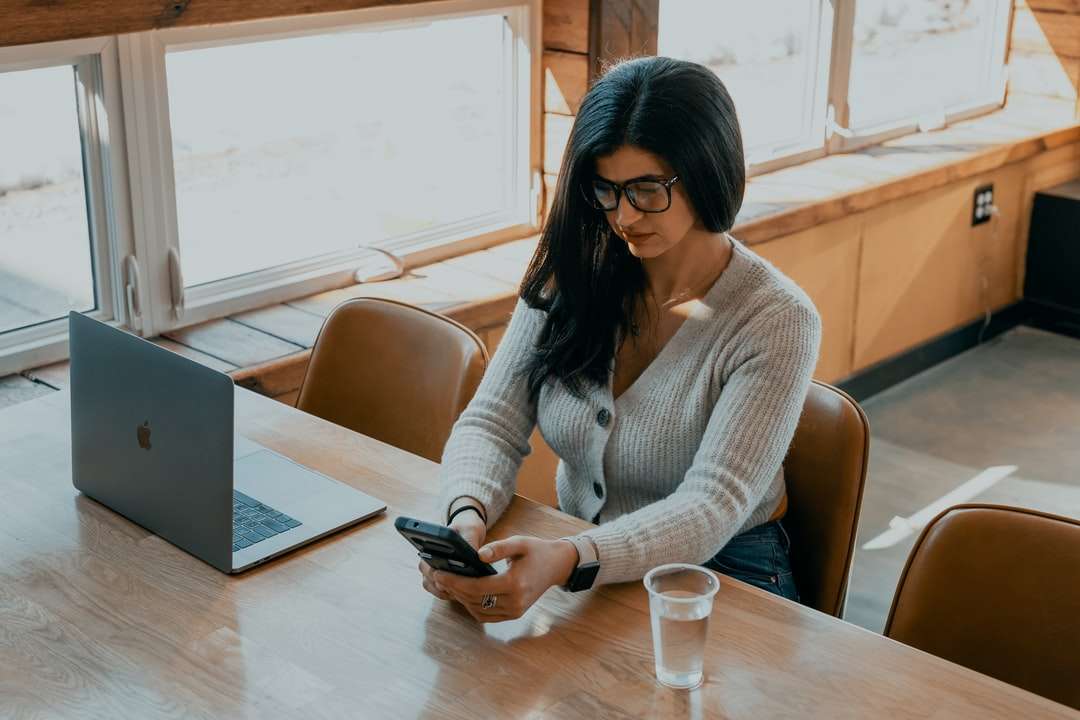 Kobieta w białym sweter obsiadaniu na krześle trzyma smartphone puzzle online
