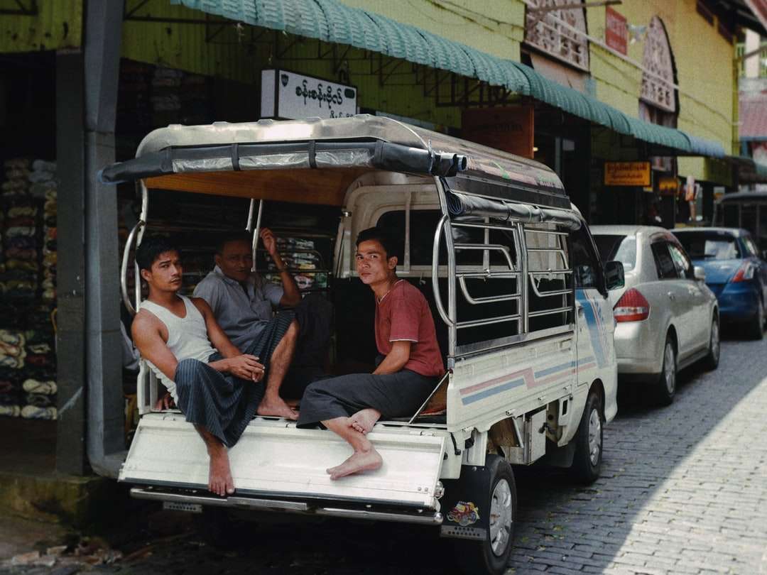 3 mężczyzn siedzący na białym i zielonym samochodzie puzzle online