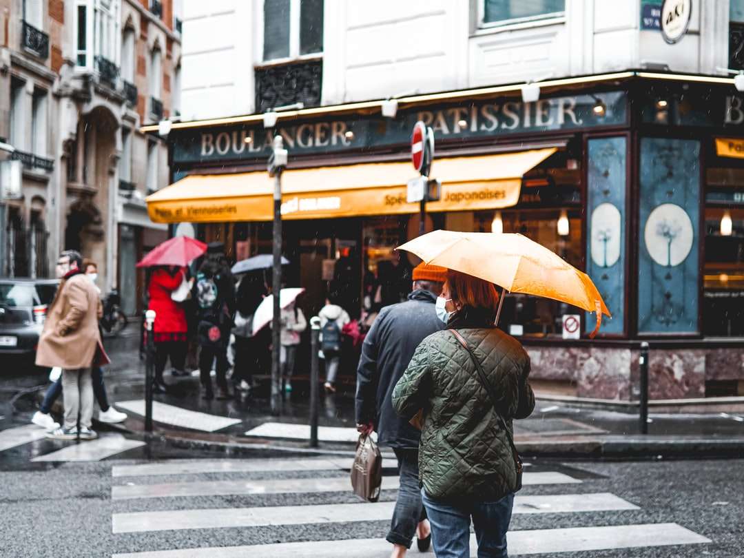 Mężczyzna w czarnej kurtce gospodarstwa parasol chodzenie na chodniku puzzle online