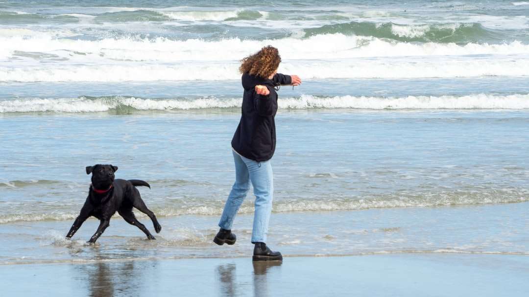 Kobieta w czarnej kurtce i białych spodniach spaceru na plaży puzzle online