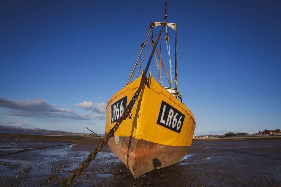Żółta i czarna łódź na brązowym piasku podczas dnia puzzle online