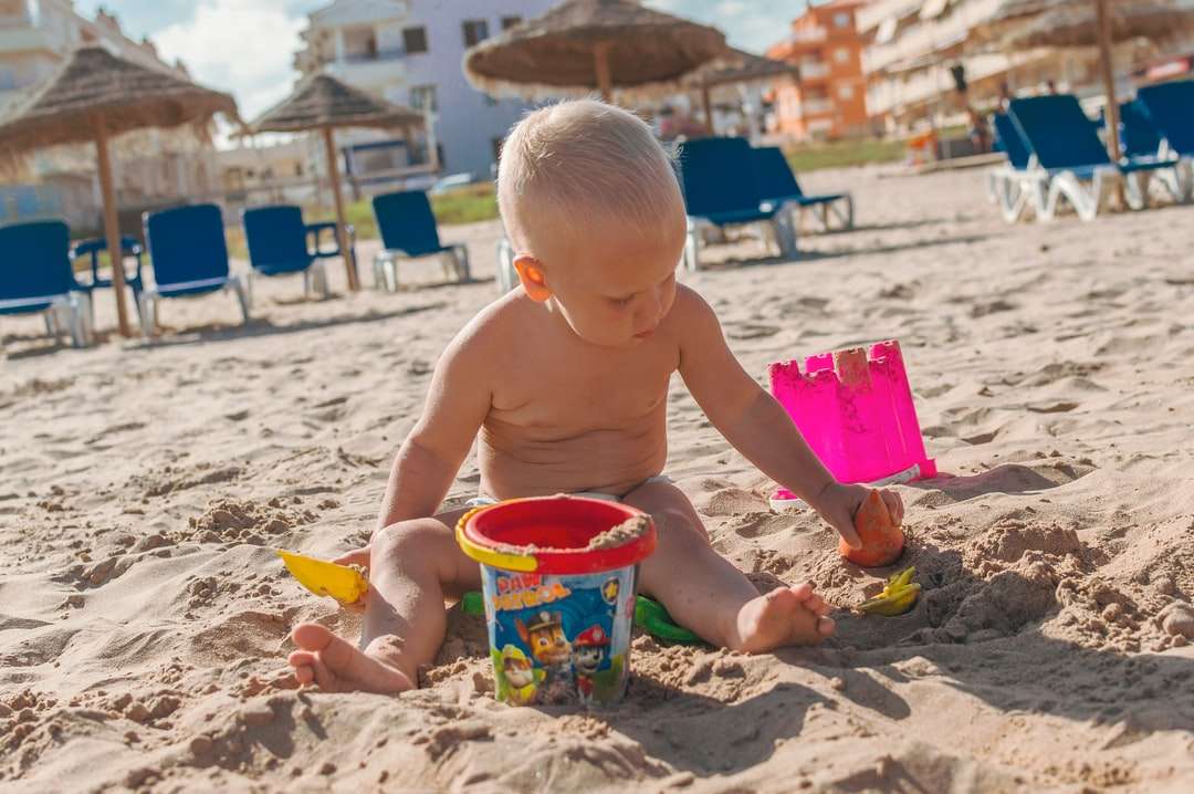 Topless Chłopiec trzyma błękitnego plastikowego wiadra na piasku puzzle online
