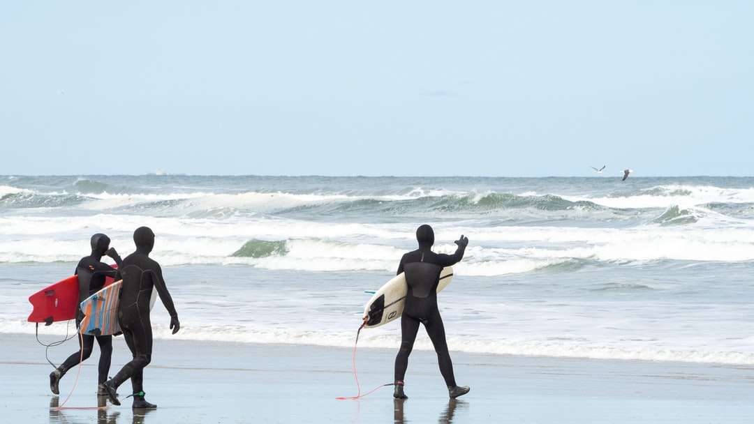 Mężczyzna w czarnych szortach trzyma białą deskę surfingową puzzle online